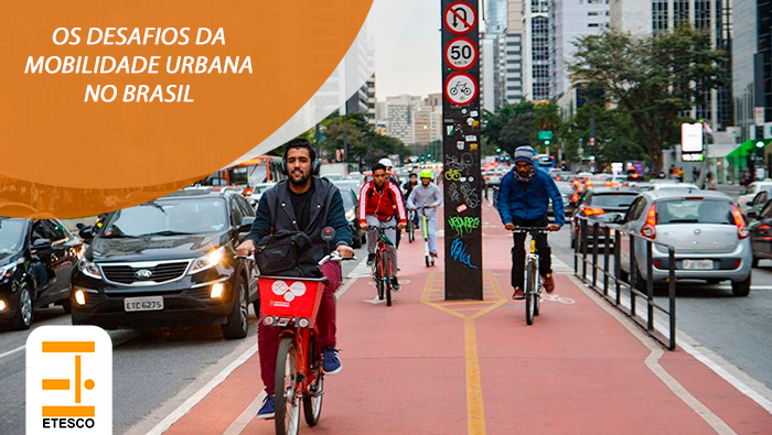 A imagem mostra pessoas andando de bicicleta na ciclofaixa de alguma avenida.